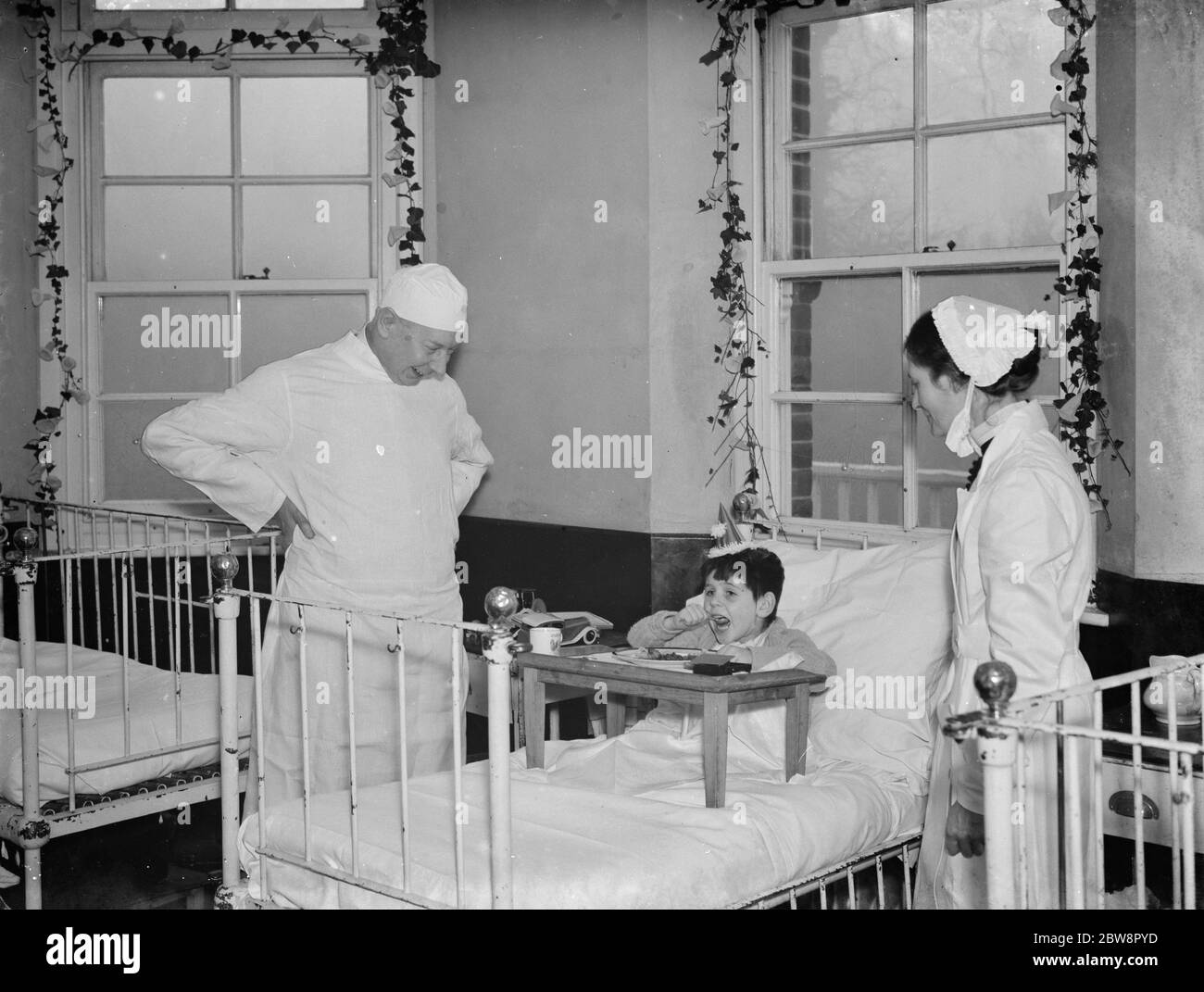 A little boy on the ward receives his christmas dinner under the watchful eye of staff at Cray Valley Hospital . 1937 Stock Photo