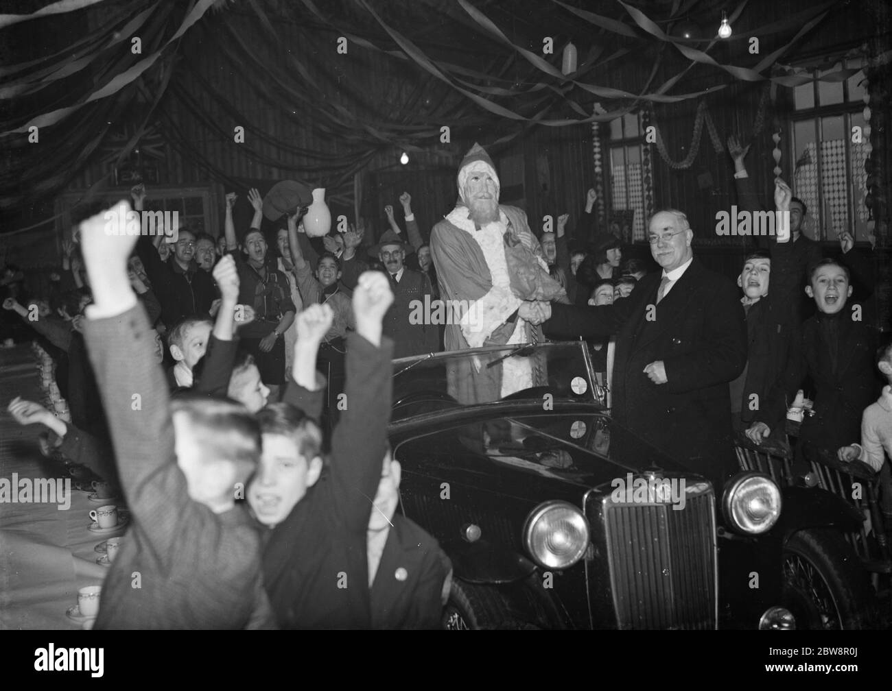 An enthusiastic welcome for Father Christmas as he arrives at a childrens ' s breakfast at Dartford in Kent . 1937 Stock Photo
