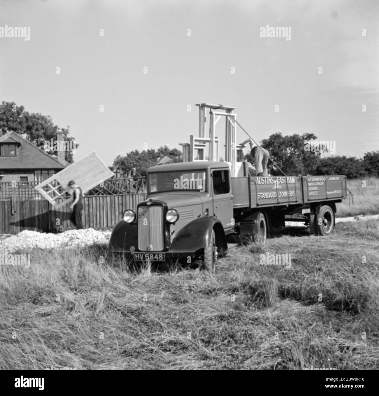 A bedford truck from Austin and Eastham standar joinery , unloads a trailer full of wooden frames . 1936 . Stock Photo