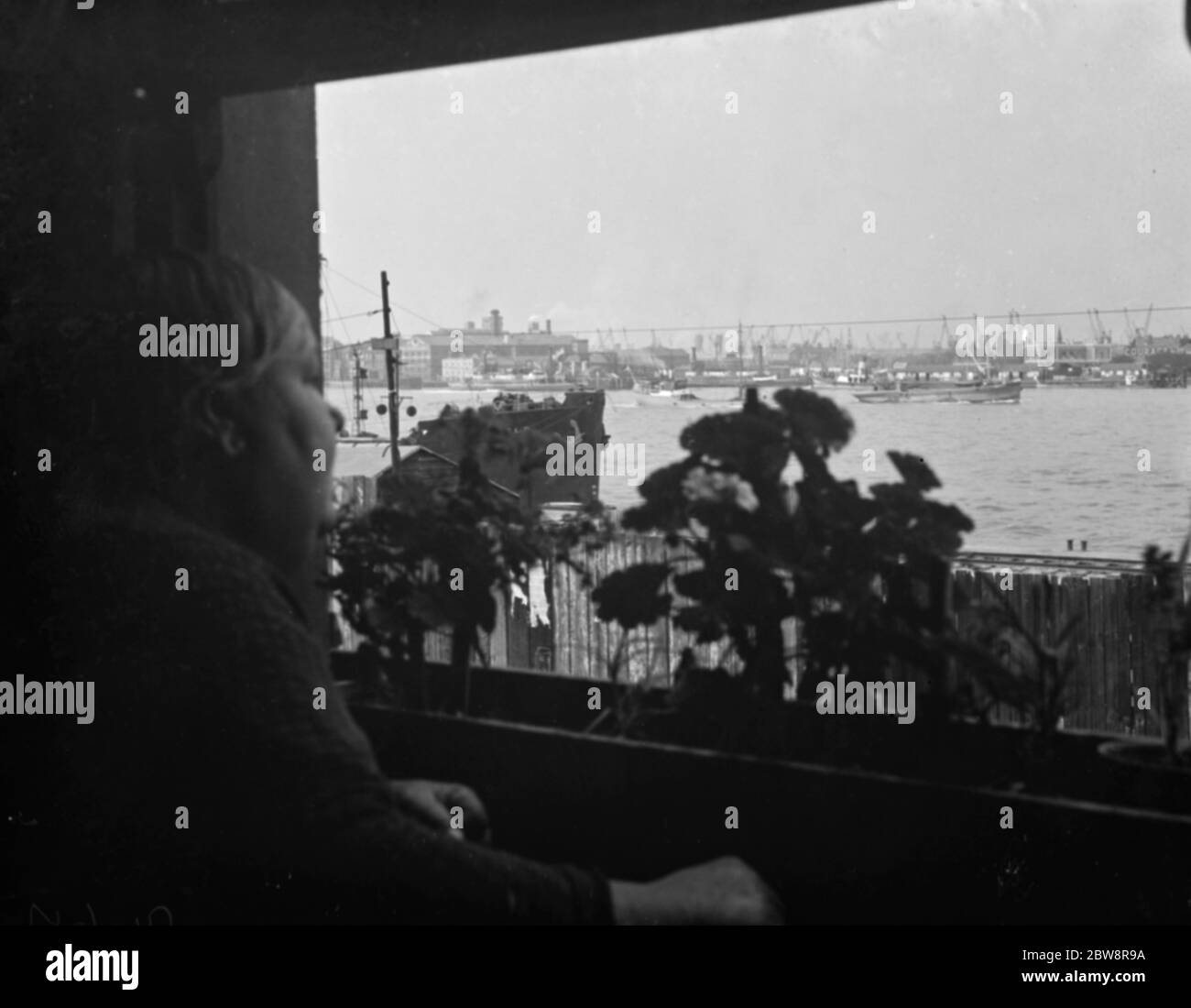 Man views Thames shipping from his window in Woolwich . 1938 Stock Photo