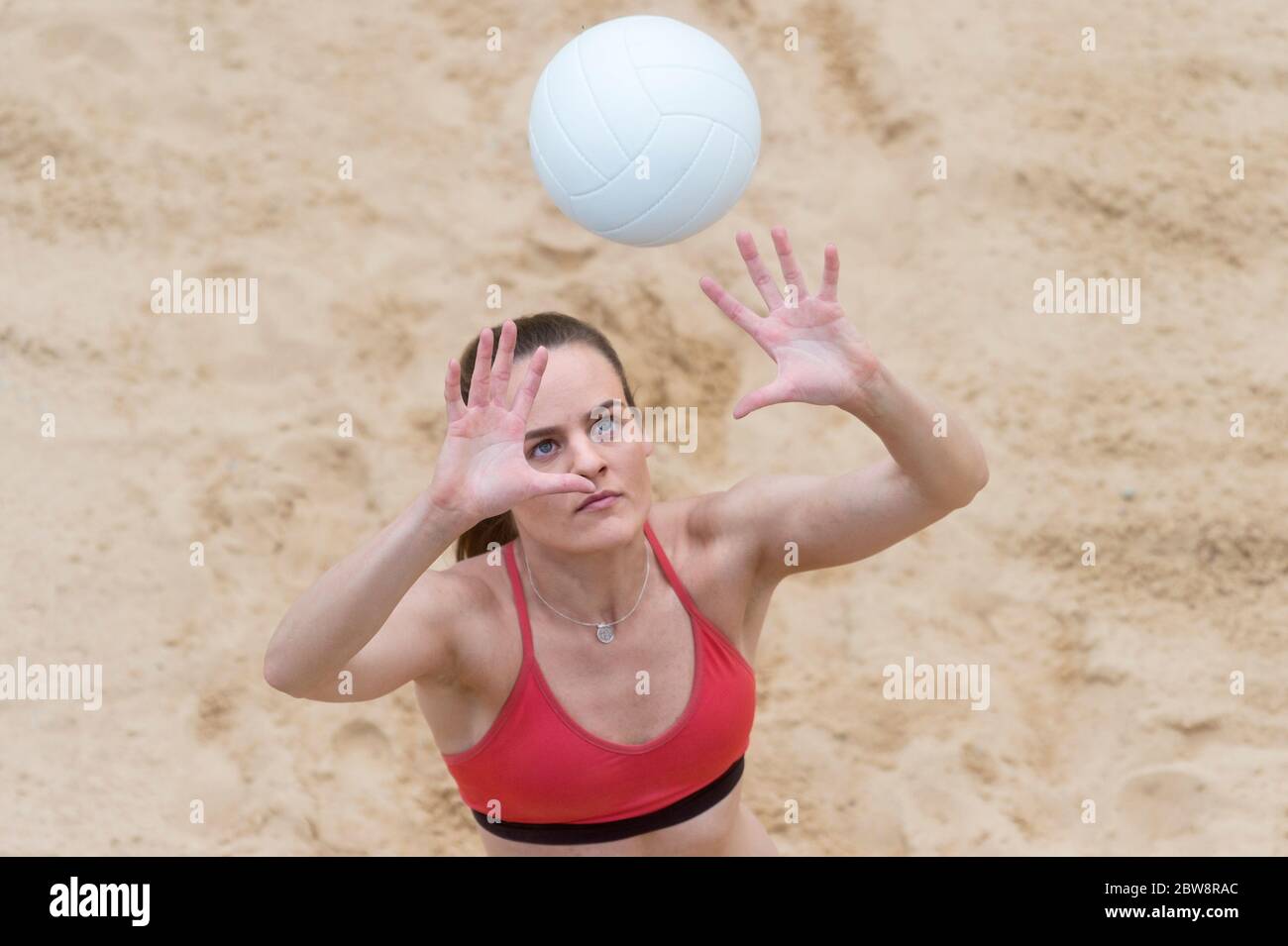 Young woman with white ball playing volleyball on beach. Summer vacation and sport concept Stock Photo