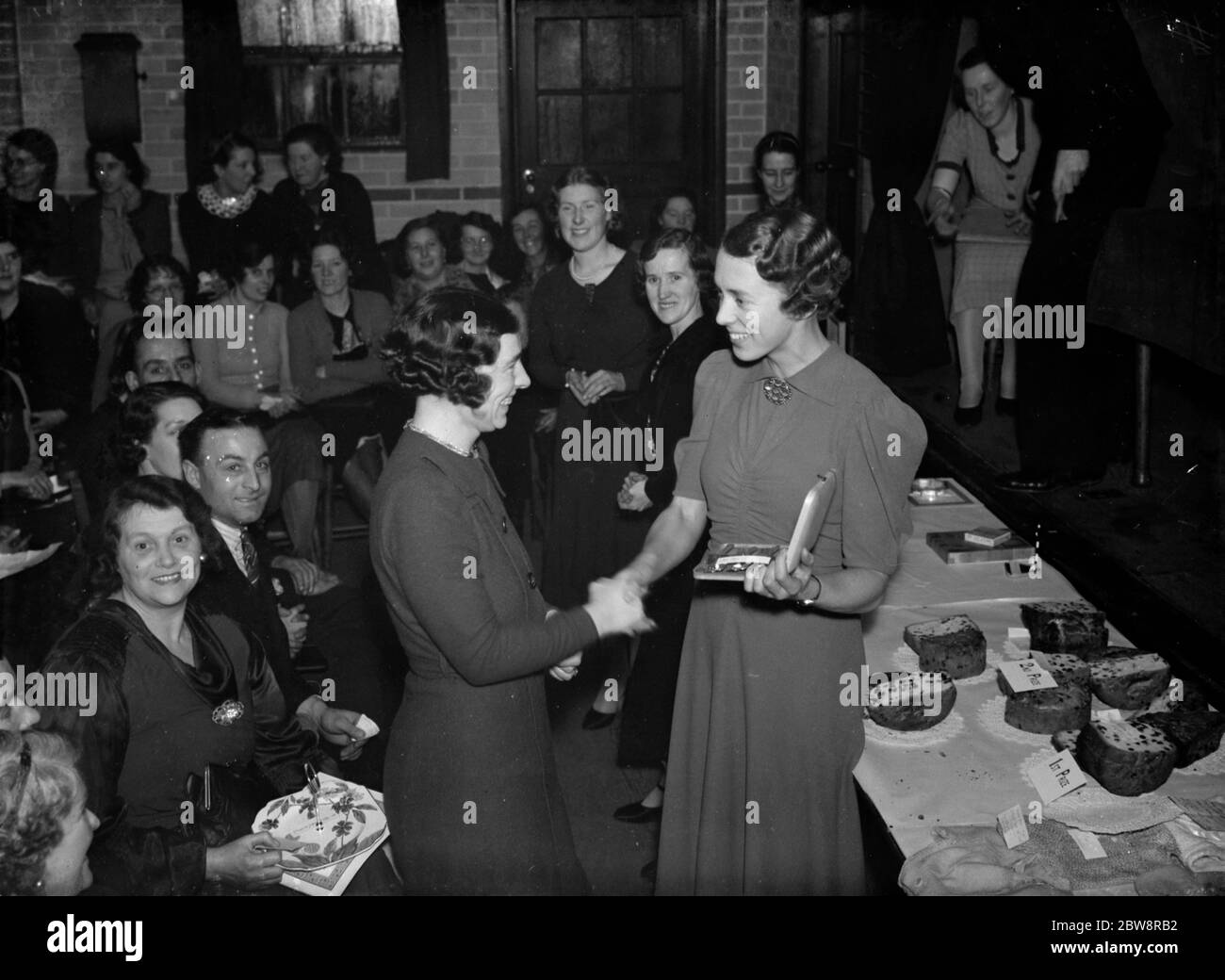 Miss Smithers receives her prize at the Days Lane Welfare Centre cake competition . 1938 Stock Photo