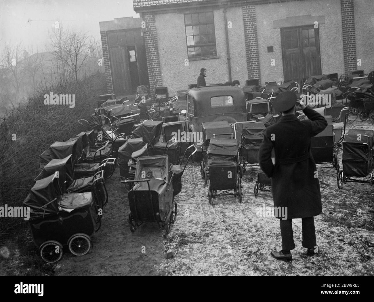 A driver scratches his head as he realises that his car is hemmed in by prams . 18 January 1936 Stock Photo