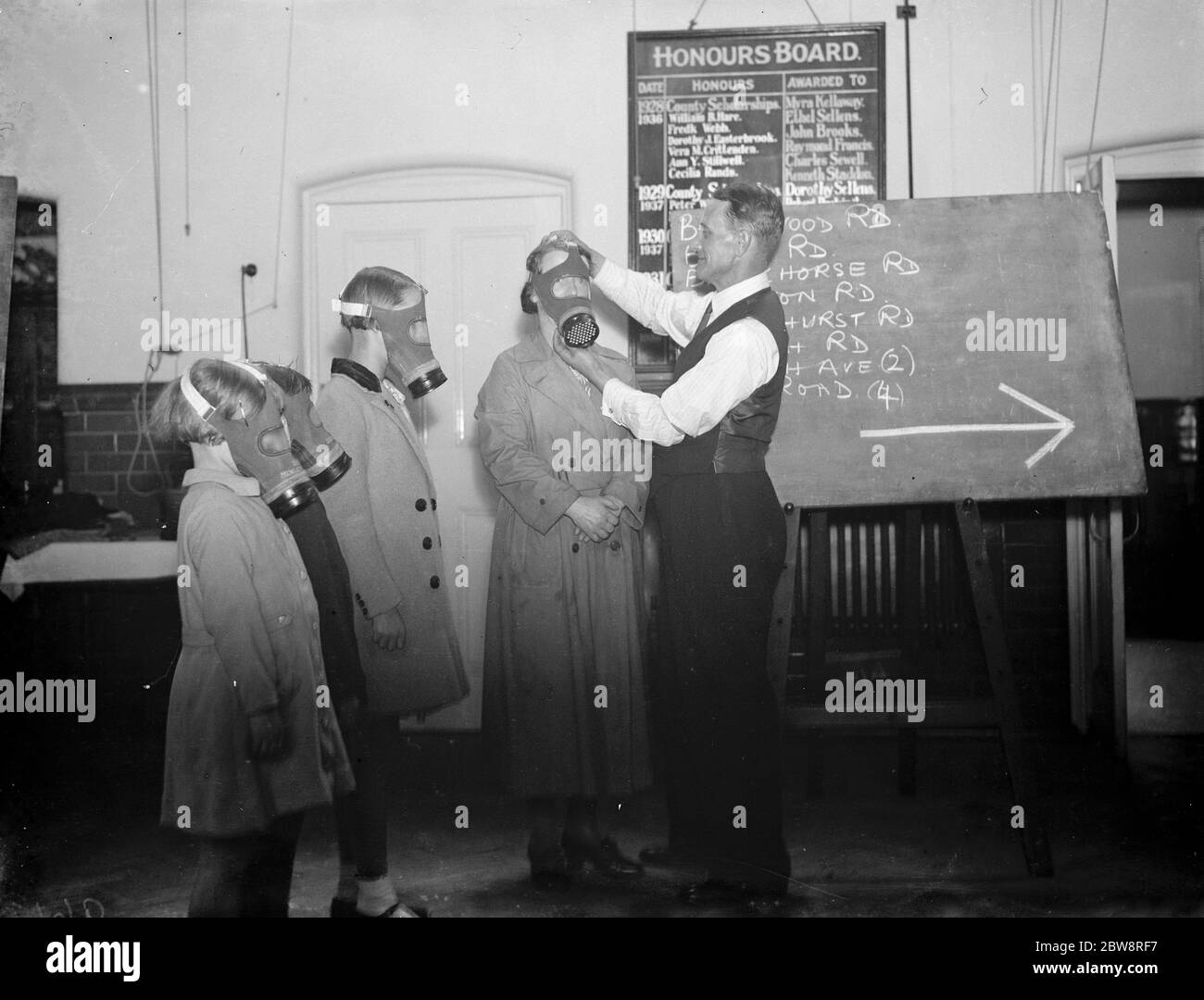 A teacher ensures children have fitted their gas masks on properly at Sidcup Hill School , London . 1938 Stock Photo