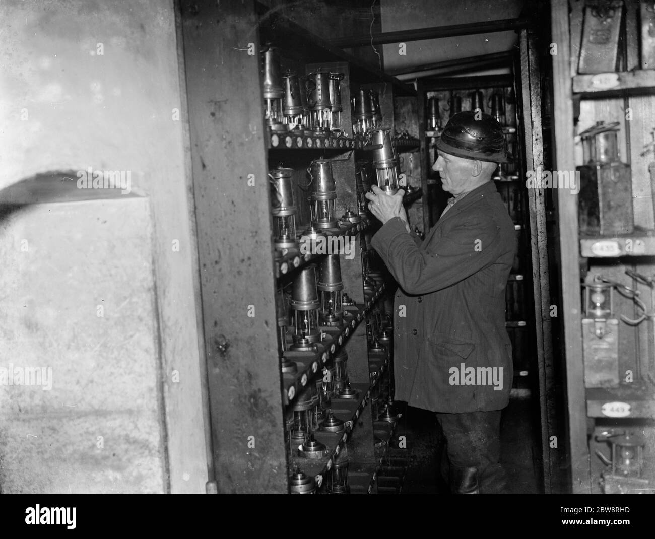 A mine worker inspecting the miner ' s lamps . 1935 Stock Photo