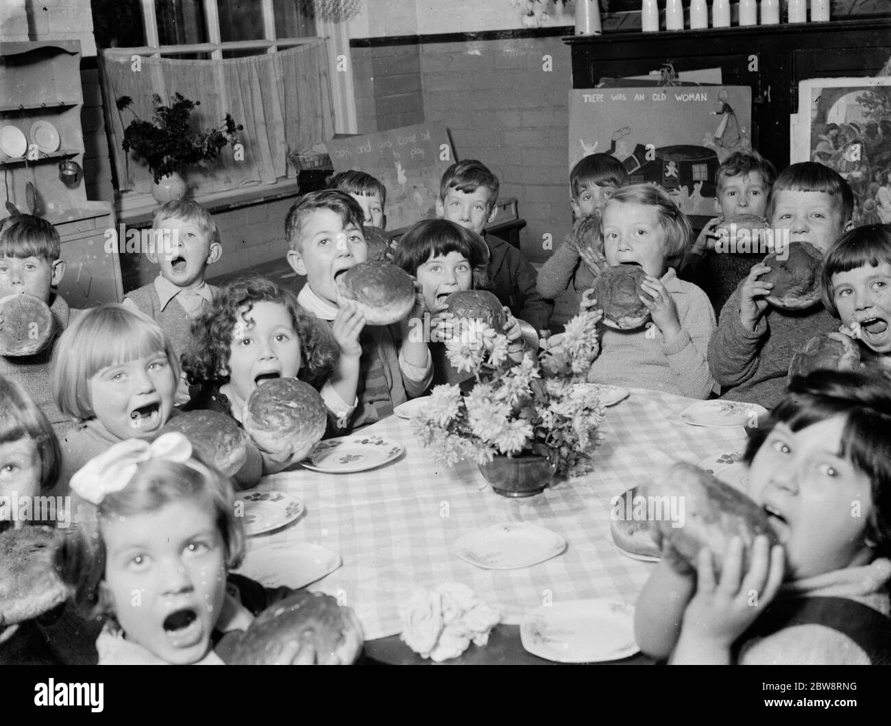 Young children about to tuck into large buns from the Guy Fawkes Charity . 1935 Stock Photo
