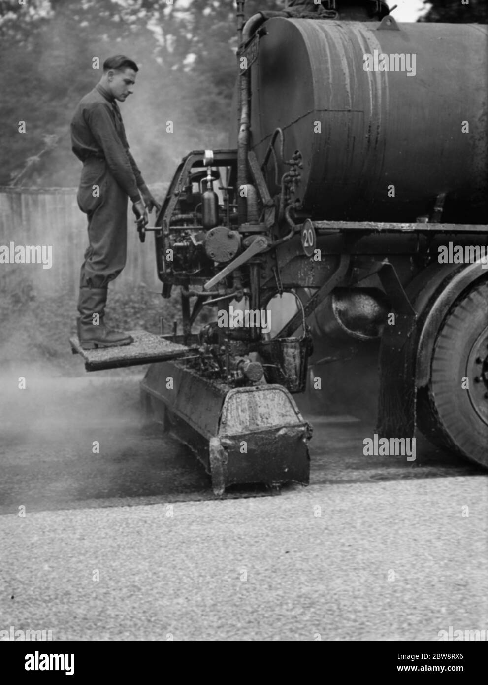 Workers are using a tar spraying machine from Taroads Limited to