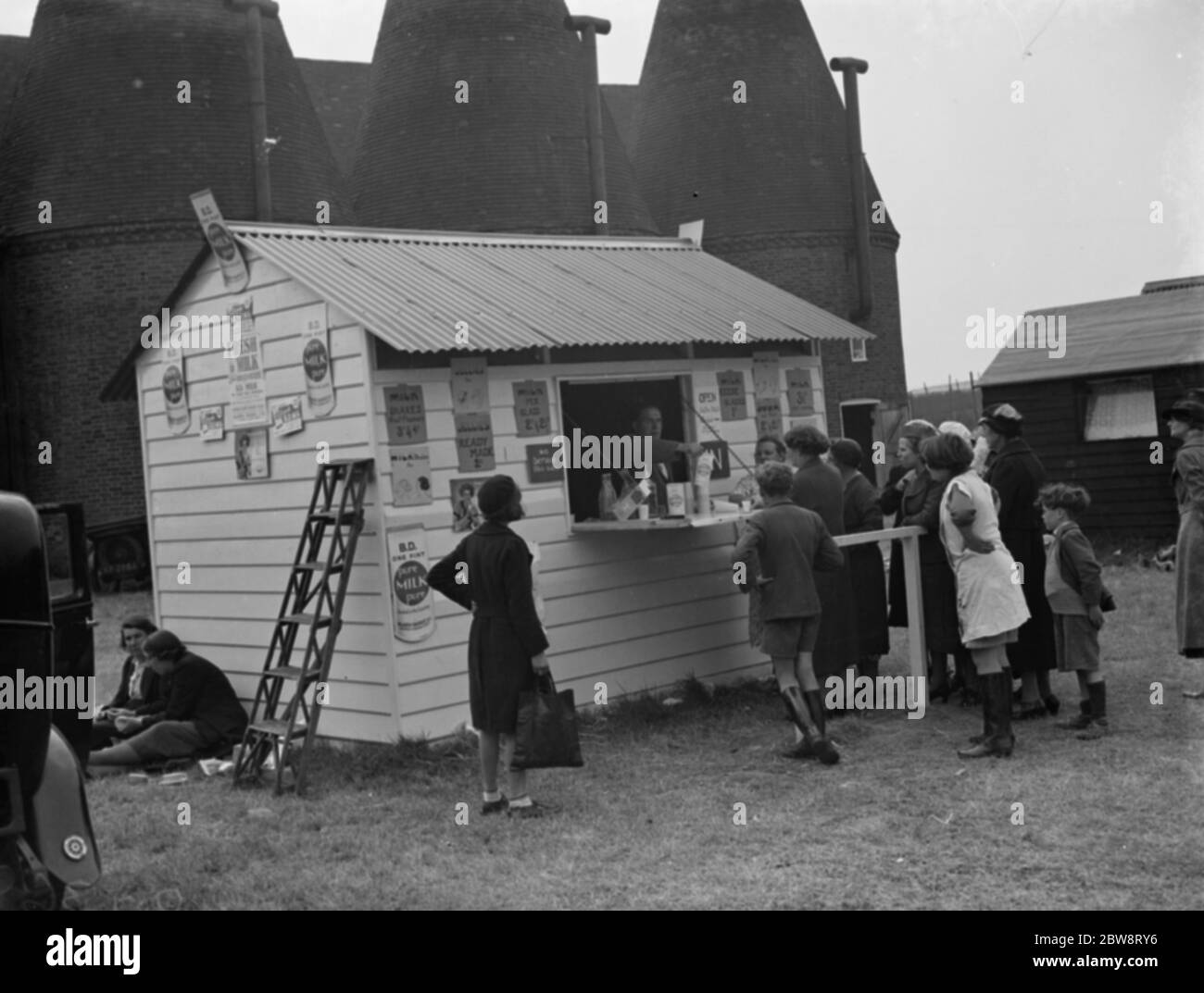 Whitbread ' s hop farm in Belting , Kent . People queuing up at the onsite milk bar . 1938 Stock Photo