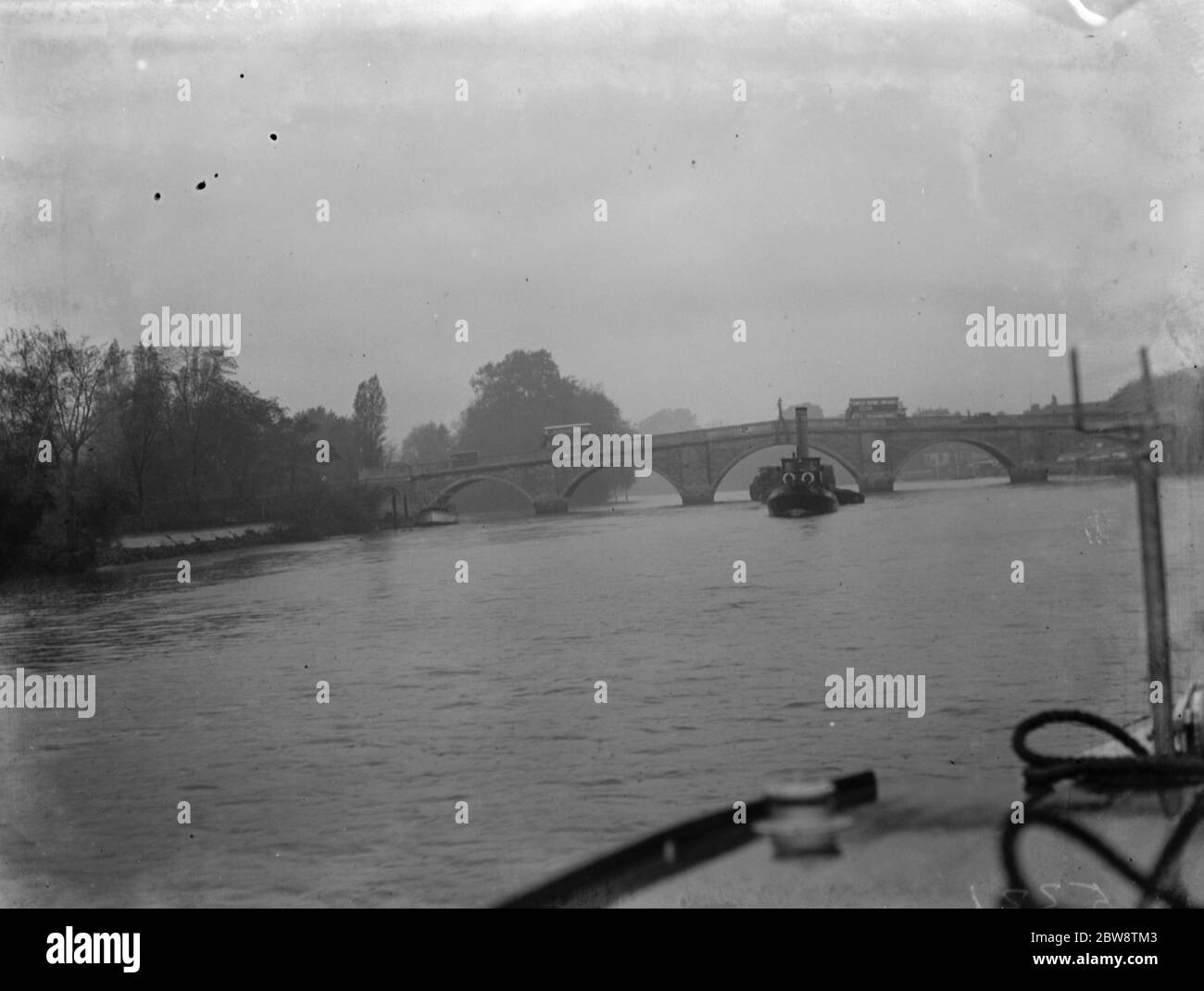 Association of Master Lightermen and Barge Owners have placed an applications for the repair of Richmond Bridge on the river Thames in London . Photos shows a tug towing a barge under the Richmond Bridge . 1936 26 October 1936 Stock Photo