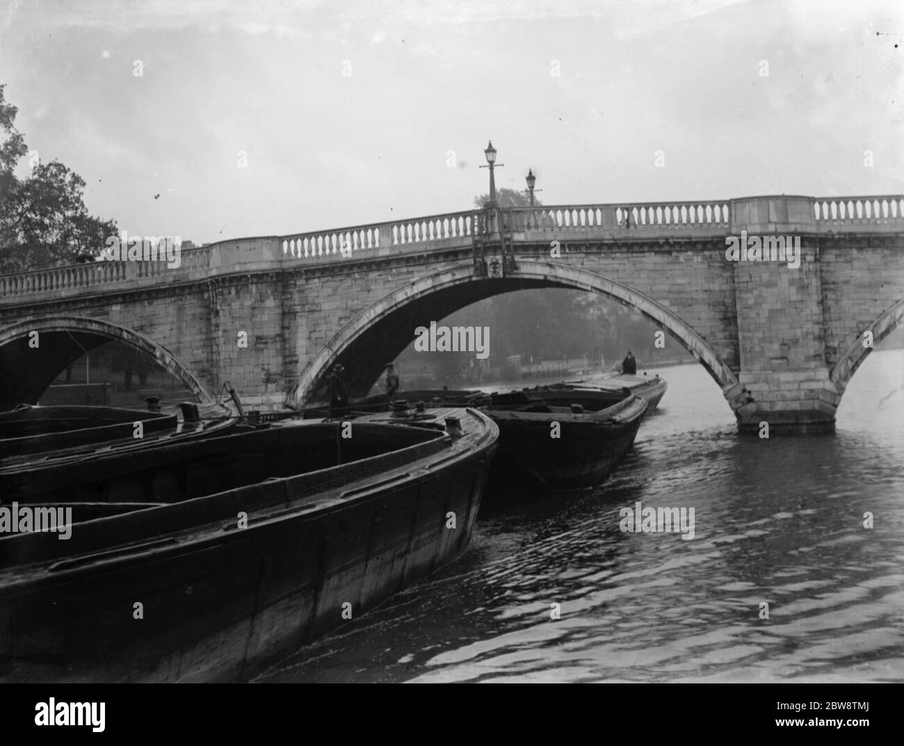 Association of Master Lightermen and Barge Owners have placed an applications for the repair of Richmond Bridge on the river Thames in London . Photos shows barges passing under the Richmond Bridge . 1936 26 October 1936 Stock Photo