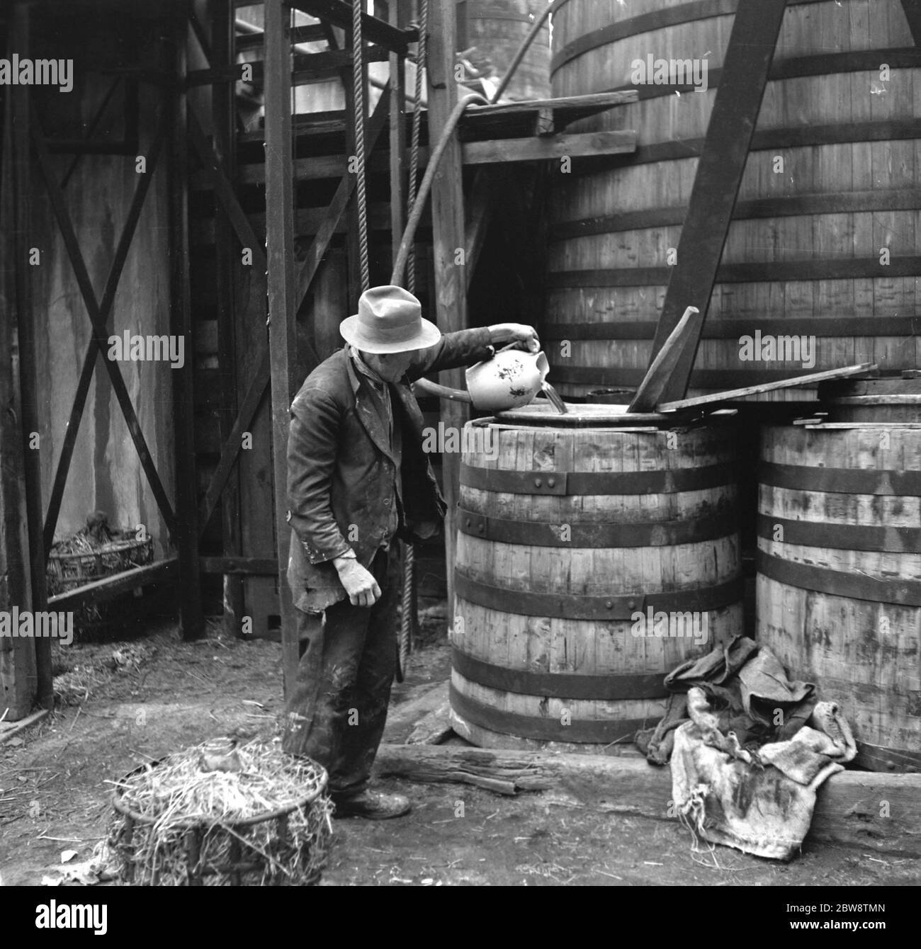 An example of primitive manufacturing methods in the 1930s, a man pours sulphuric acid onto cadmium bars at the Tyke and Kings Chemical Works . 1936 Stock Photo