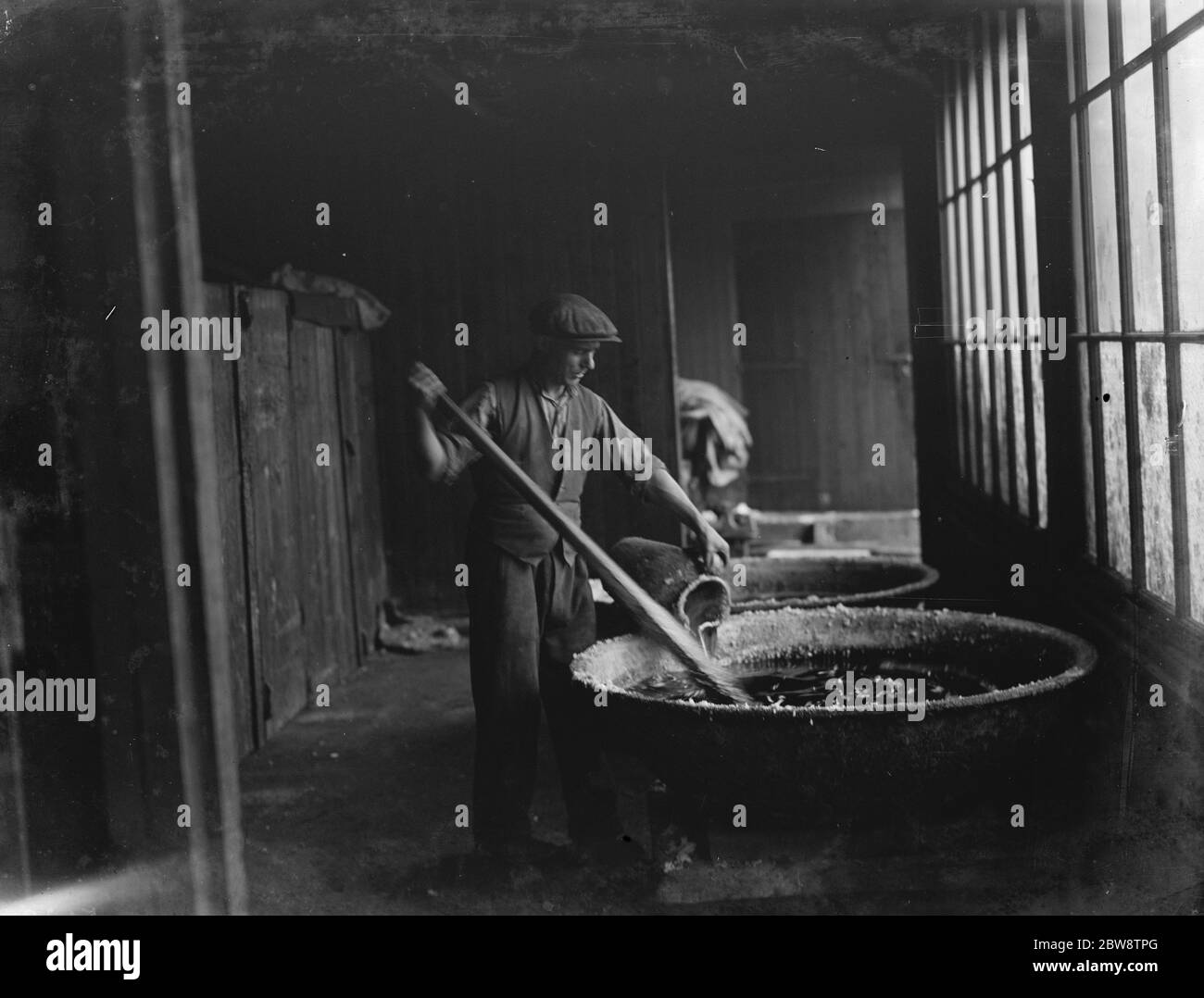 An example of primitive manufacturing methods in the 1930s , a man pours sulphuric acid onto cadmium bars at the Tyke and Kings Chemical Works . 1936 Stock Photo