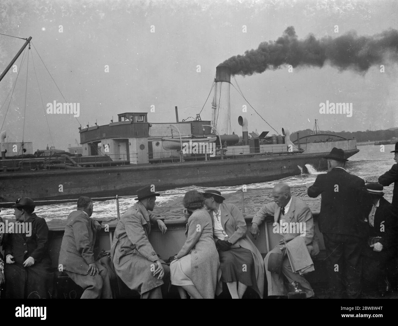 Passangers aboard a boat view the Thames shipping in Woolwich , London . A ferry crosses the river . 1938 Stock Photo