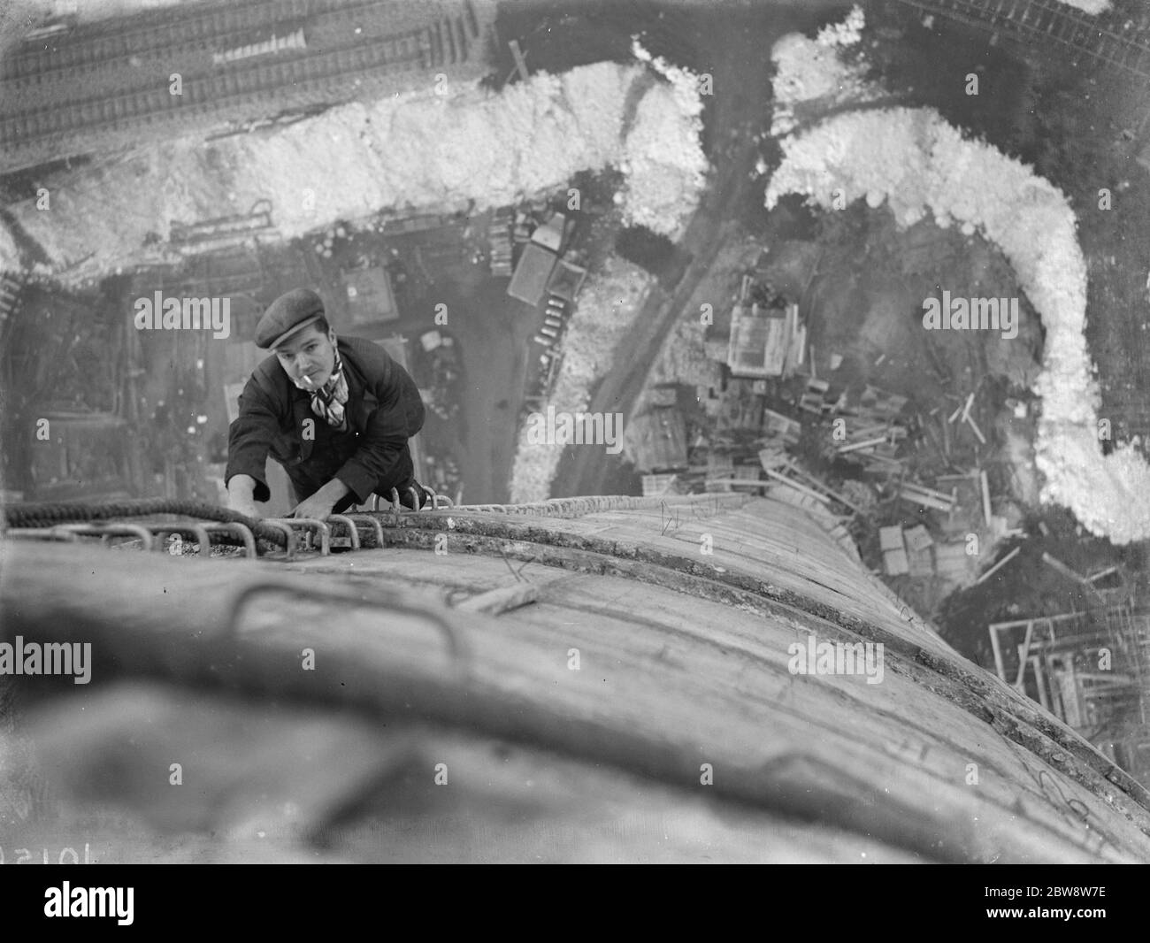 A workman climbs up on of the chimneys of the new coal electric power station under construction near Dartford , Kent . 1938 Stock Photo