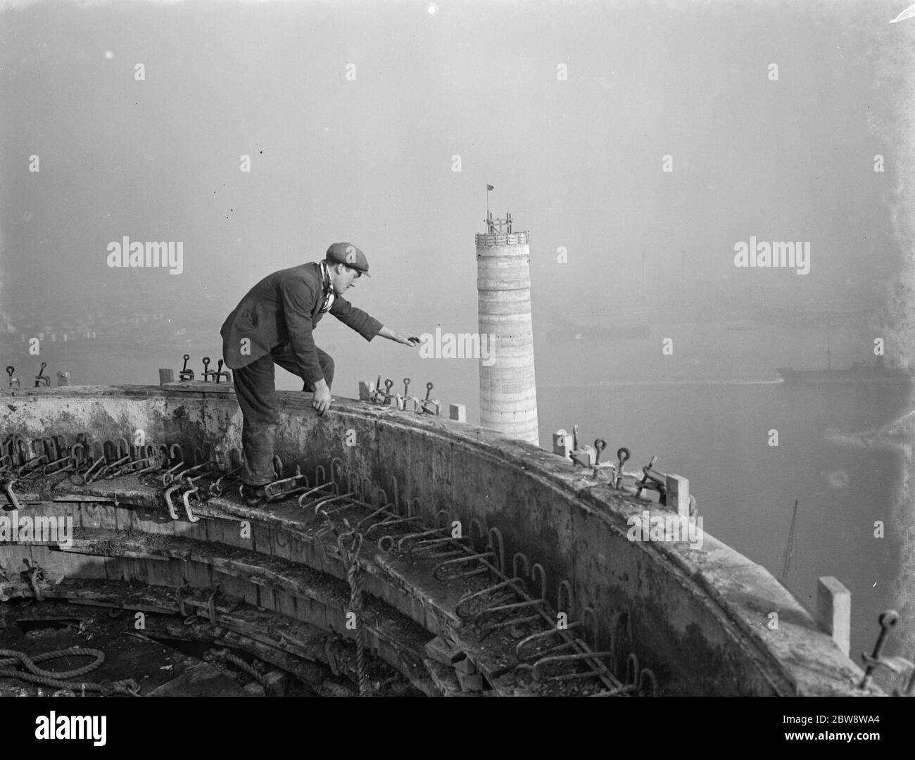 A workman waves down from one of the chimneys of the new coal electric power station under construction near Dartford , Kent . 1938 Stock Photo
