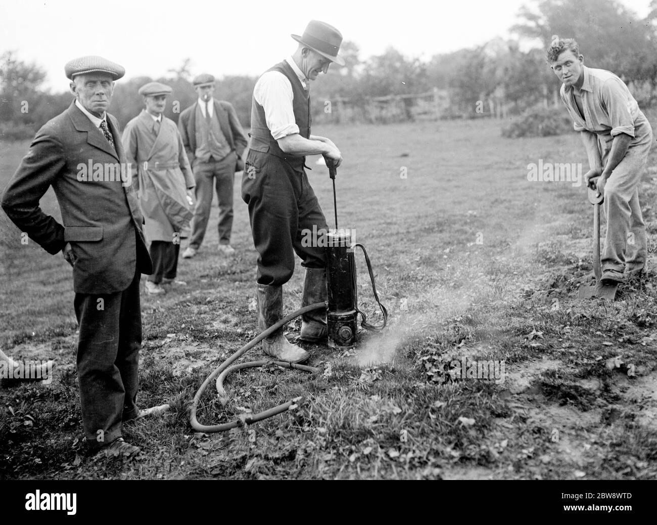 Pest controllers fill in the rabbit burrows after injecting in the poisonous Cyanogas . 1936 Stock Photo