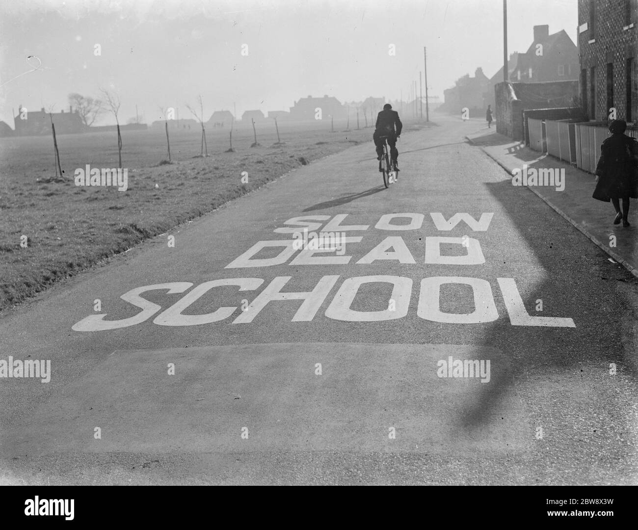 A school sign painted on the road warning road users they are approaching a school area . 1939 Stock Photo