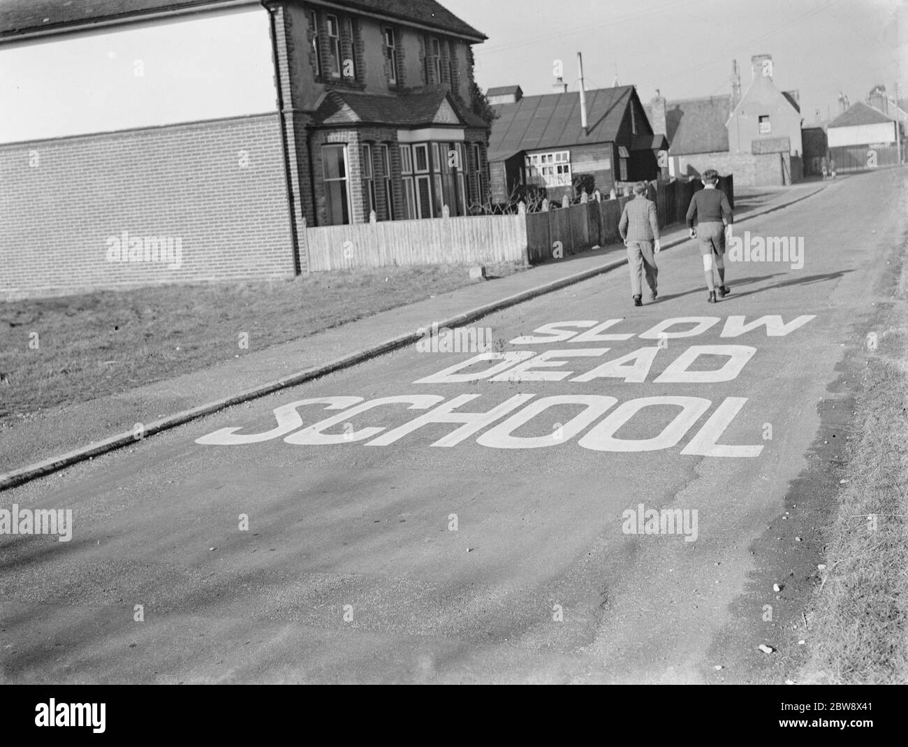 A school sign painted on the road warning road users they are approaching a school area . 1939 Stock Photo