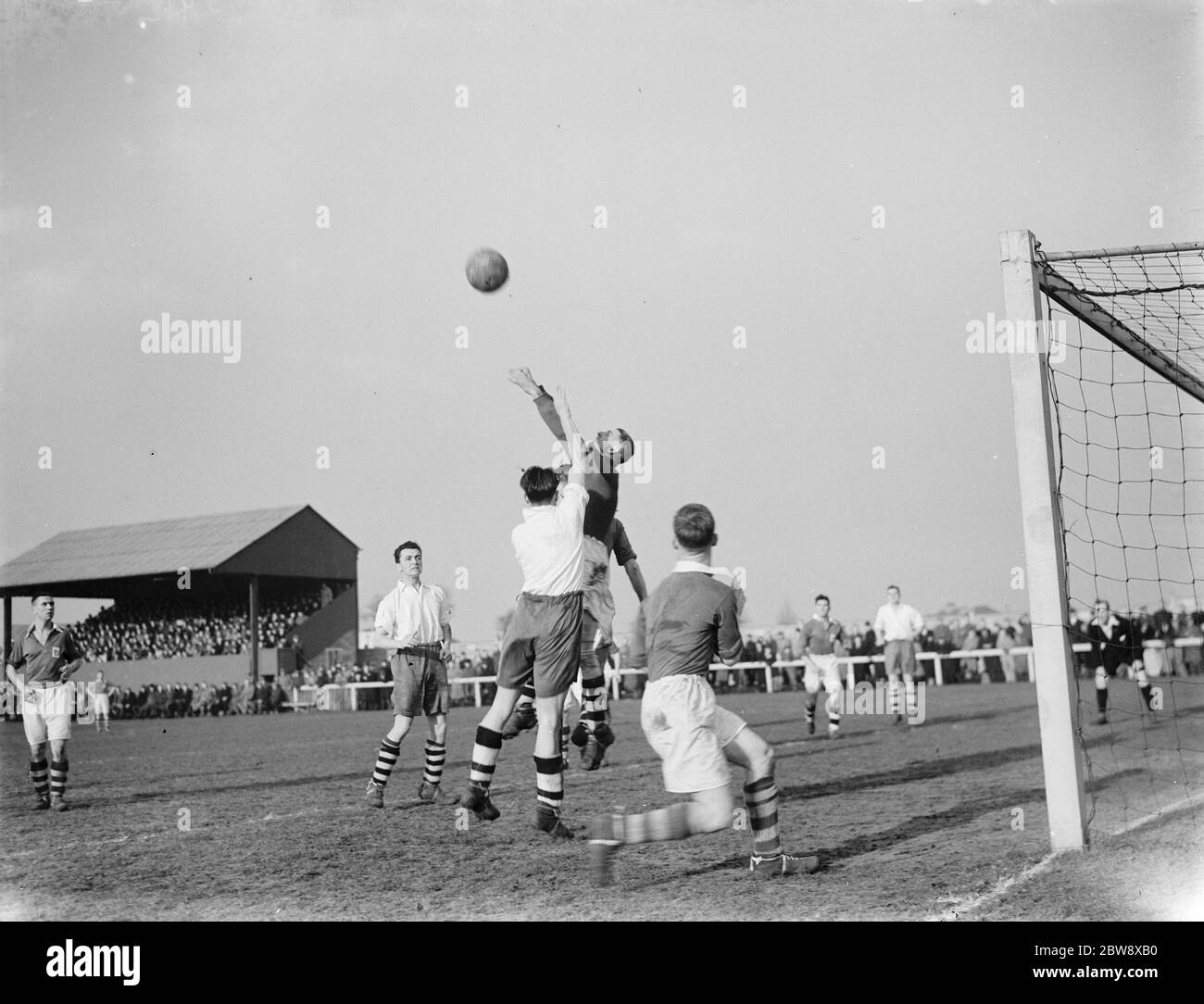 London Paper Mills vs. Leyton - FA Amateur Cup - Gordon Bennett punches clear of a Leyton forward - 27/02/37 Players compete for the ball in the air . 1937 Stock Photo