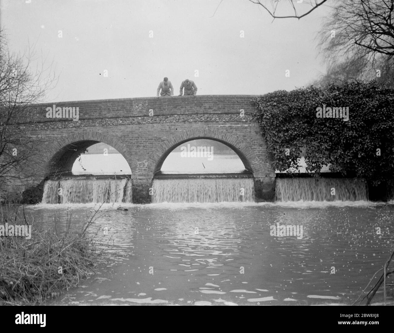 Young men look over the edge of the Northcray bridge as the water falls over the weir . 1938 Stock Photo