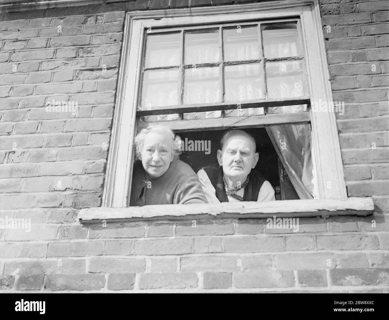 Mr George Dowe and and Mrs Dowe looking out of their window in Northfleet , Kent . 1938 . Stock Photo