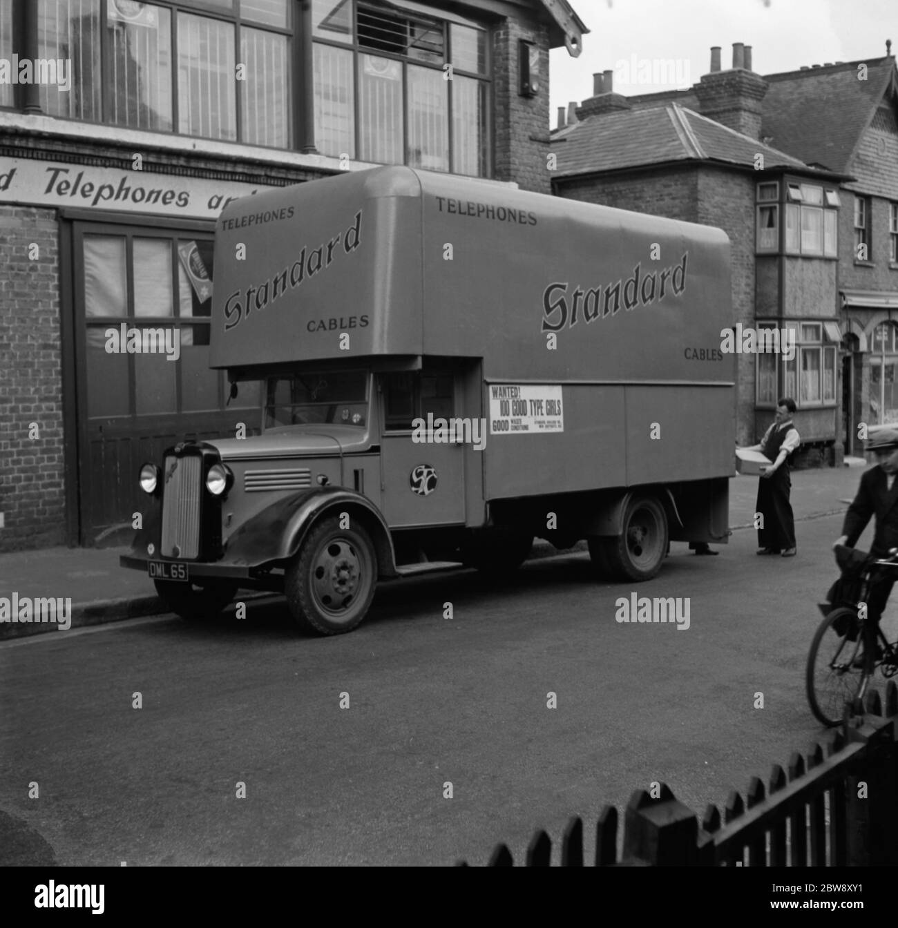 A worker loads boxes into a Bedford truck belonging to the Standard Telephone and Cables Company Ltd , parked outside their store . 1936 . Stock Photo