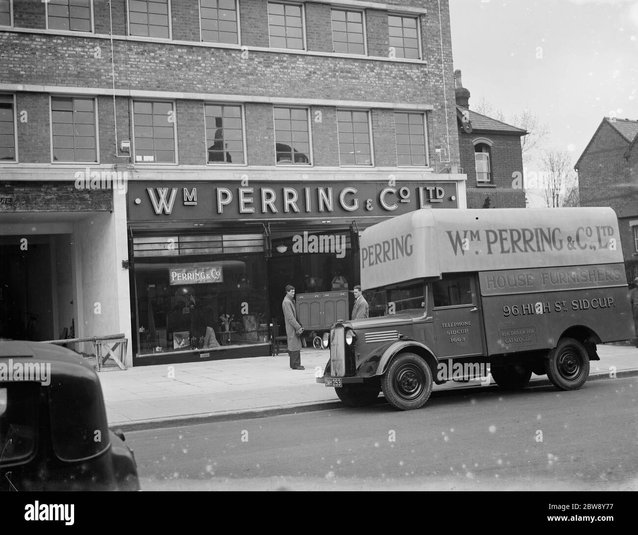 A Bedford truck belonging to W Perring and Co Ltd , the house furnishers . Workers are loading a cupboard onto the truck at their the company 's store in Sidcup , Kent . 1936 . Stock Photo