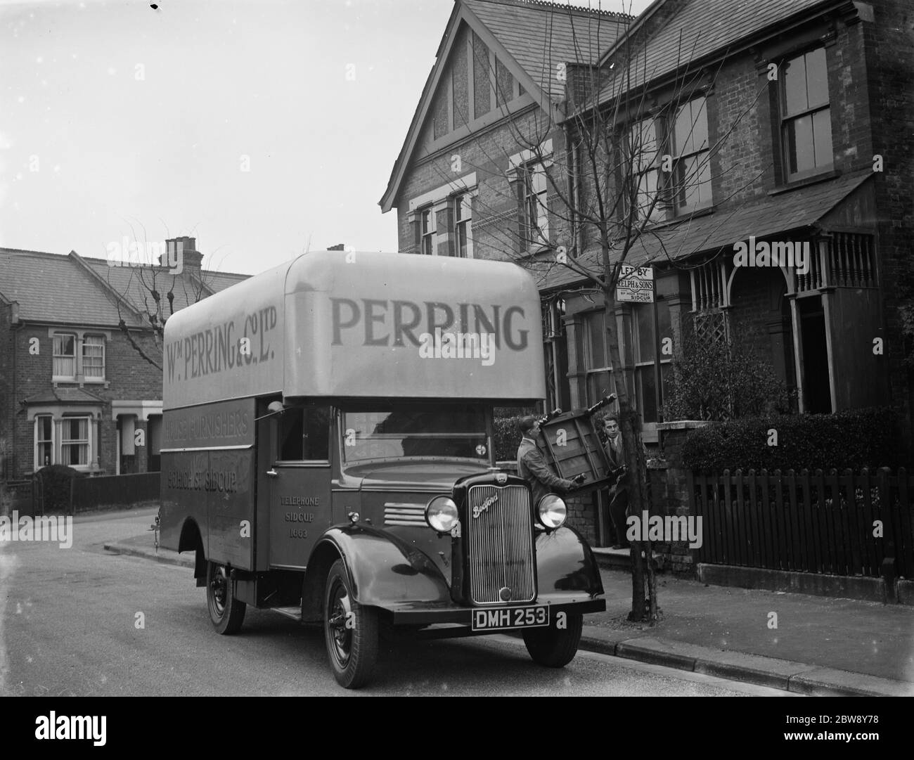 A Bedford truck belonging to W Perring and Co Ltd , the house furnishers based in Sidcup , Kent . Workers are delivering a table . 1936 . Stock Photo