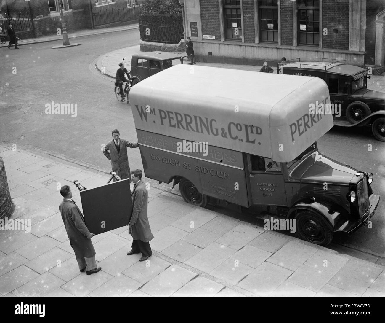 A Bedford truck belonging to W Perring and Co Ltd , the house furnishers . Workers are loading a table onto the truck at their the company 's store in Sidcup , Kent . 1936 . Stock Photo