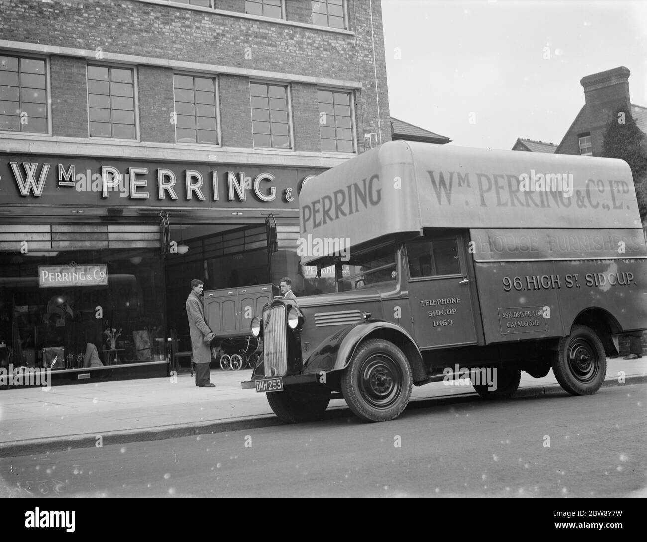 A Bedford truck belonging to W Perring and Co Ltd , the house furnishers . Workers are loading a cupboard onto the truck at their the company 's store in Sidcup , Kent . 1936 . Stock Photo