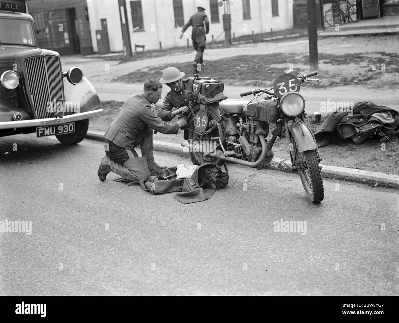 An army motorcyclist performs some maintenance on his Royal Enfield 25 CC motorcycles rear wheel . 1939 Stock Photo
