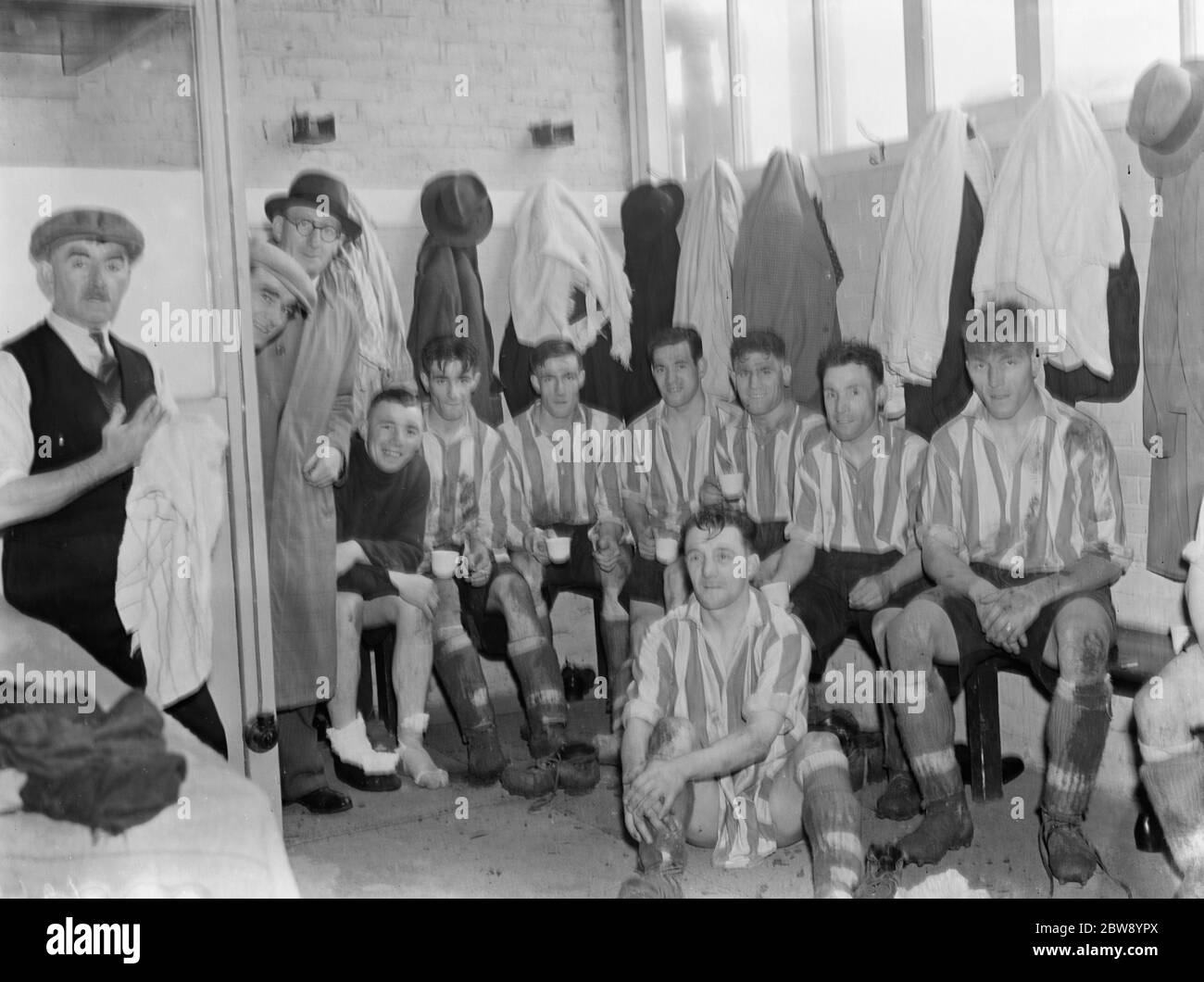 Dartford - Players after their victory over Guildford City. Scorer Joe Harron is on the floor. Manager Bill Collier is peeping around the door. - 17/04/37 Dartford Club dressing room , footballers . 1937 Stock Photo