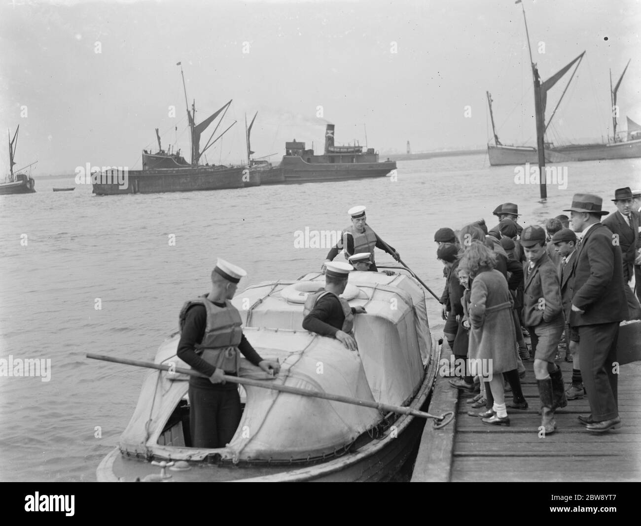 The Home Fleet on the river Thames at Greenhithe , Kent . School children on a floating dock cue up to board a boat . 1937 Stock Photo