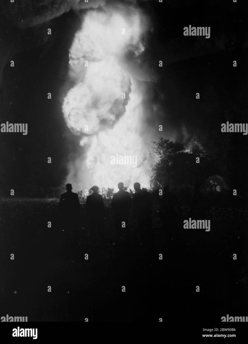 The silhouetted figures of men can be seen against the flames and smoke from the fire at the tire dump in Ruxley , Kent . 2 June 1937 Stock Photo