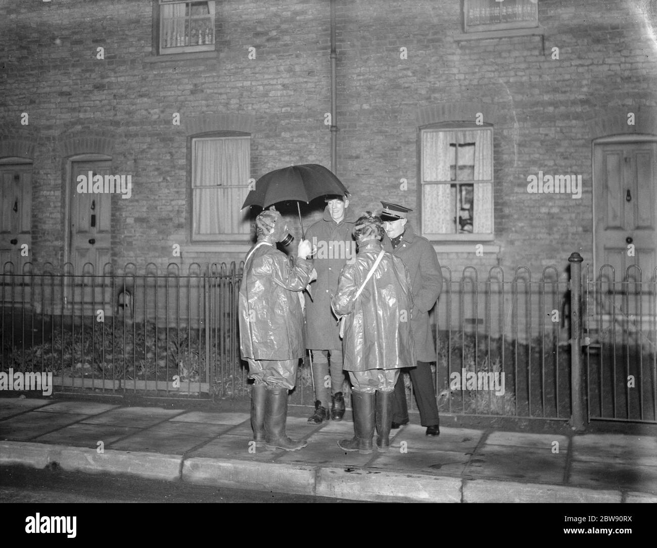 Air Raid Precautions wardens taking cover underneath an umbrella . 1938 . Stock Photo