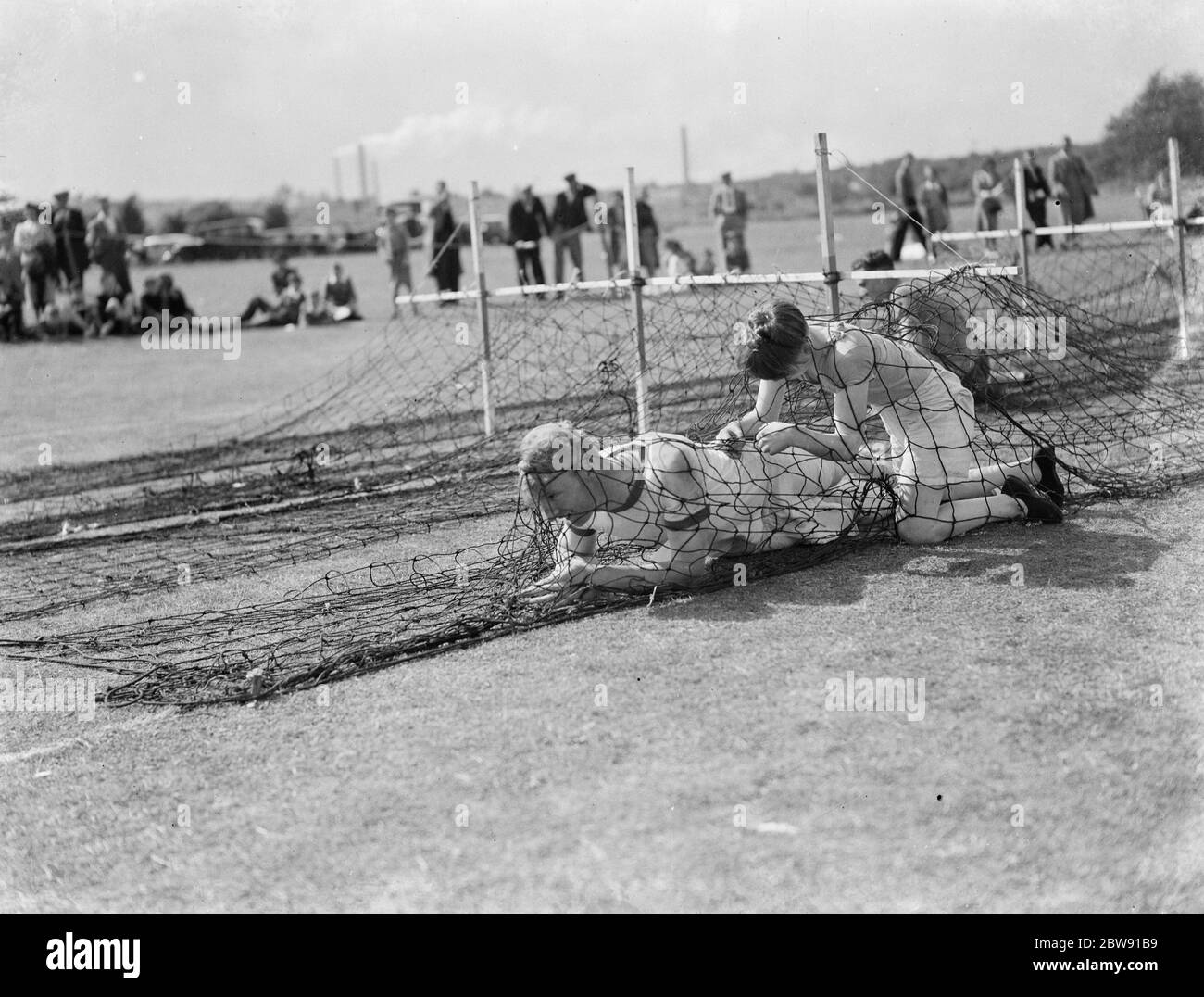 Children crawling through the nets during the obstacle race at the PBM sports day . 1939 Stock Photo