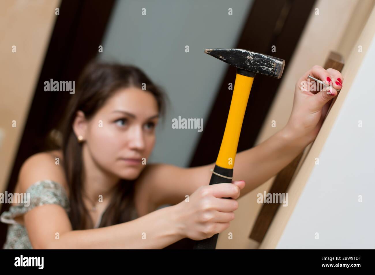 Girl is going to hammer a nail into the wall for photo frame Stock