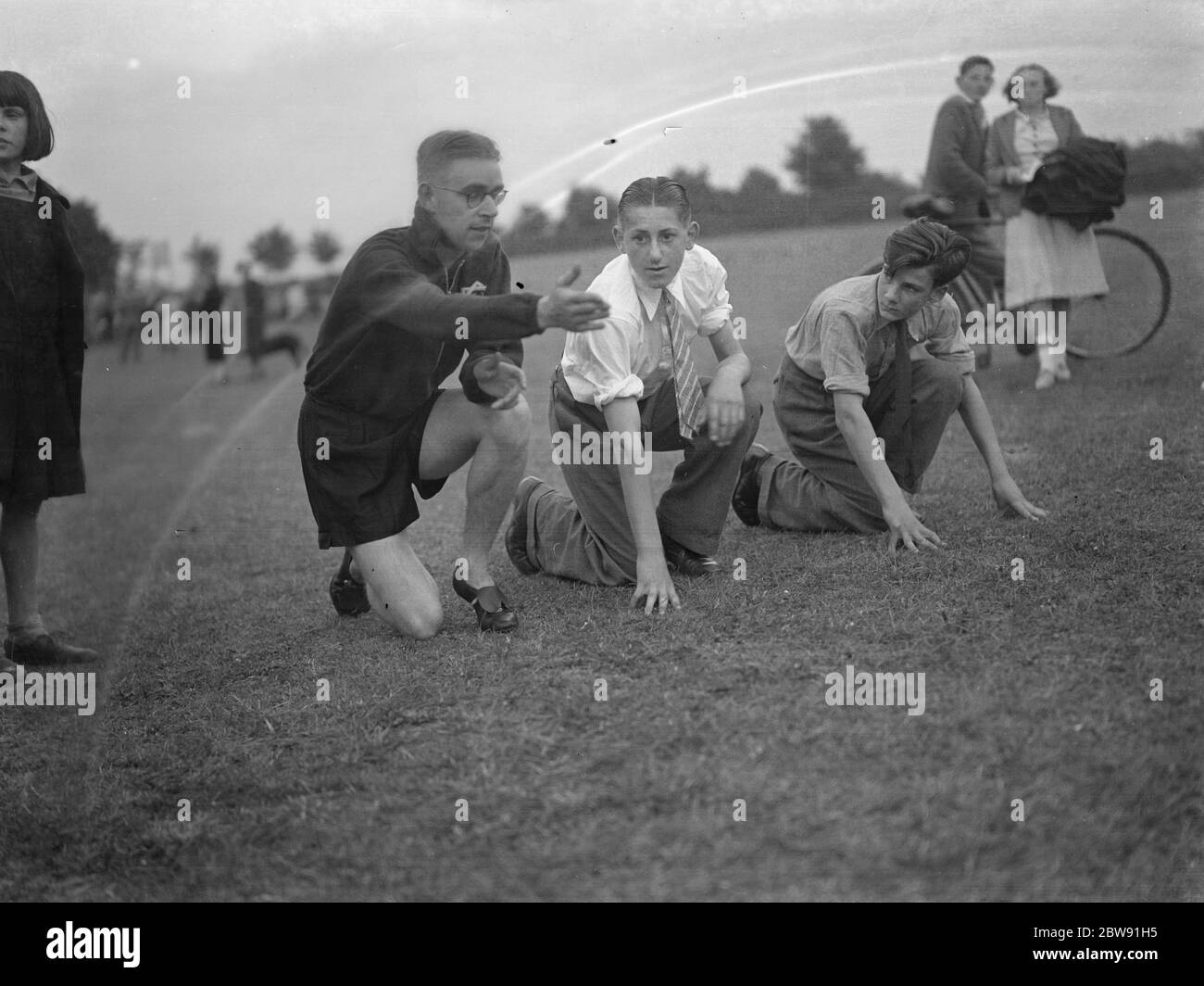 Sydney Wooderson , the great British middle distance runner and mile world record holder , teaches boys the sprinting start technique . 1939 Stock Photo