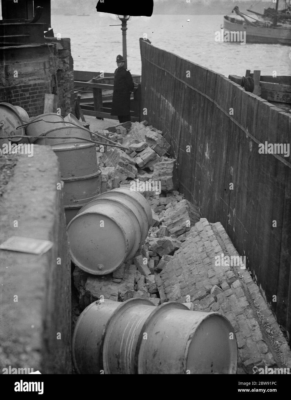 A collapsed wall by the river at Greenwich showing the debris ; oil drums and bricks . 1938 Stock Photo