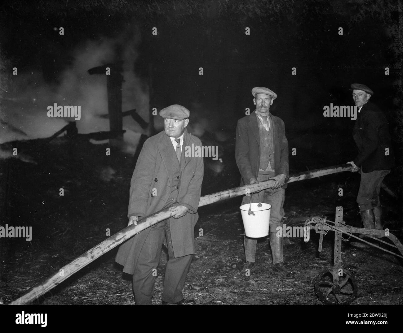 A fire at Chaplin ' s Farm , Hockenden . Farm workers hold the hoses . 1938 Stock Photo
