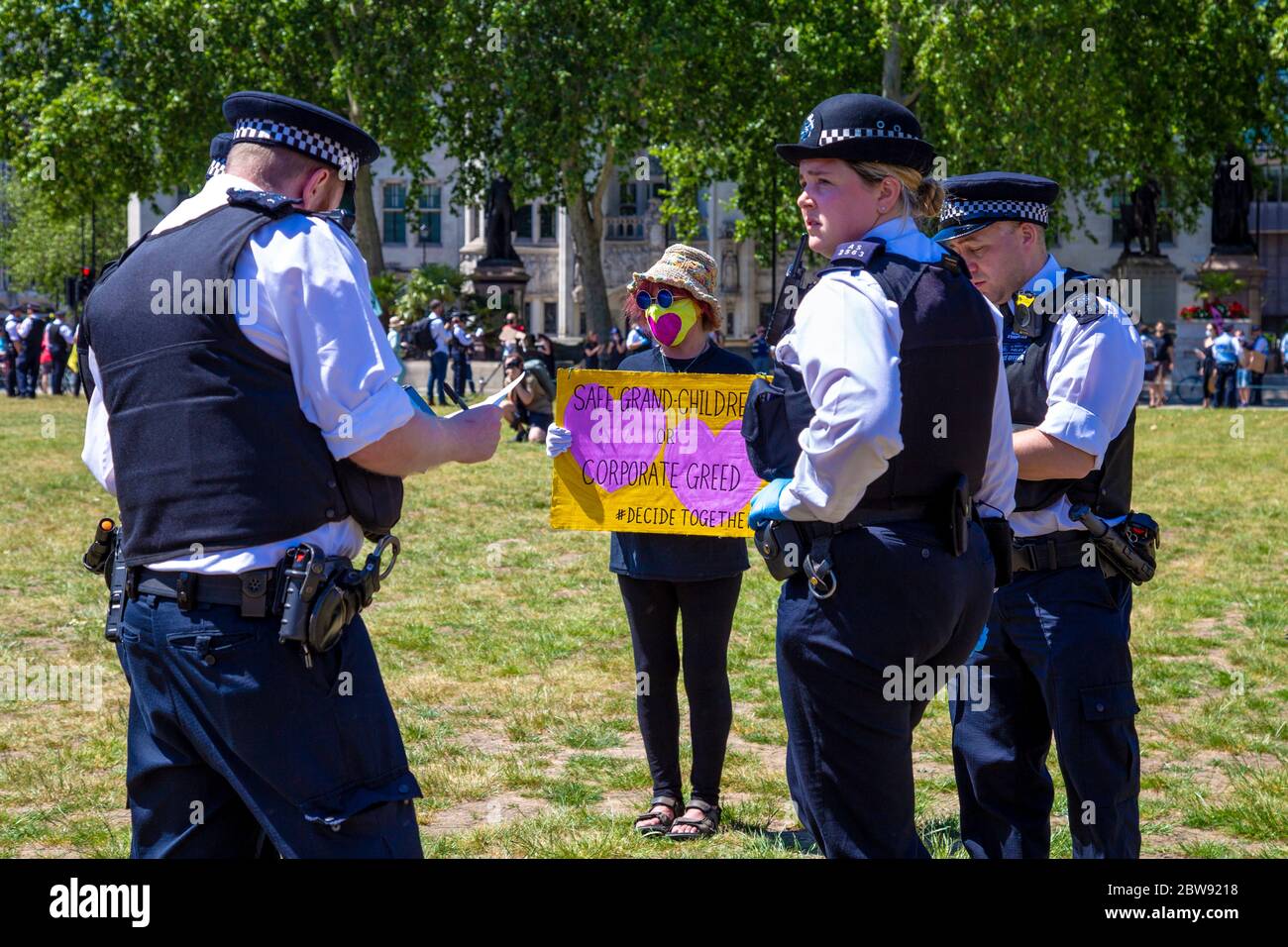 30 May 2020 London, UK - Extinction Rebellion stage silent socially-distanced climate change protest in Westminster, protesters being fined and taken away by police for breaching coronavirus regulations, police officers writing a fine ticket to a female protester in face mask Stock Photo
