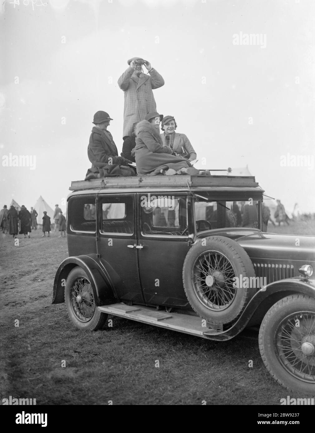Spectators climb on to the roof of their car to get a good view of the R A Woolwich point to point . 1936 Stock Photo