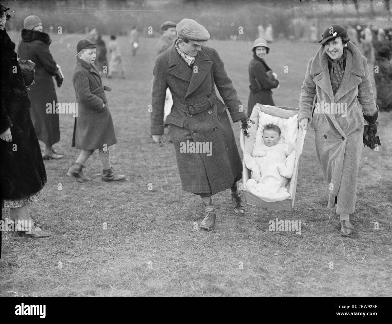 A young fan being carried to the races at the R A Woolwich point to point by baby carrier . 1936 Stock Photo