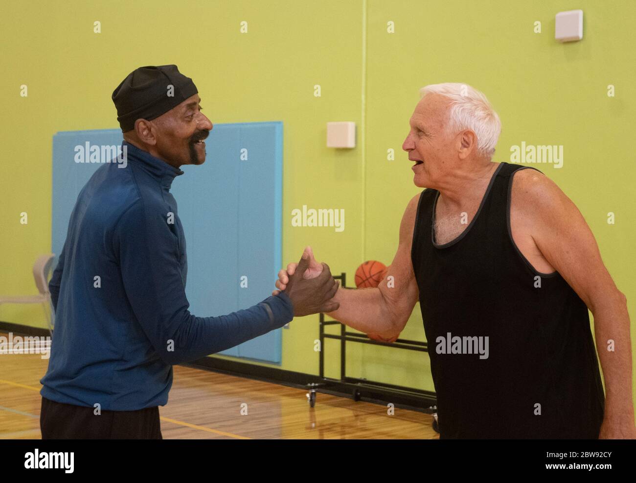 Two senior basketball players shake hands after completing in a senior