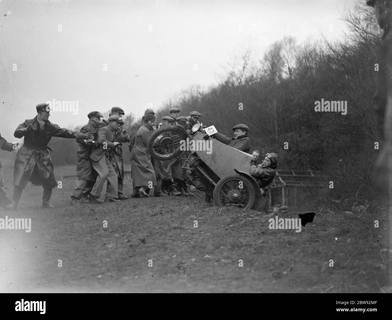 A group of men pull a motorbike out of a ditch after it lost control during the race . 1939 . Stock Photo