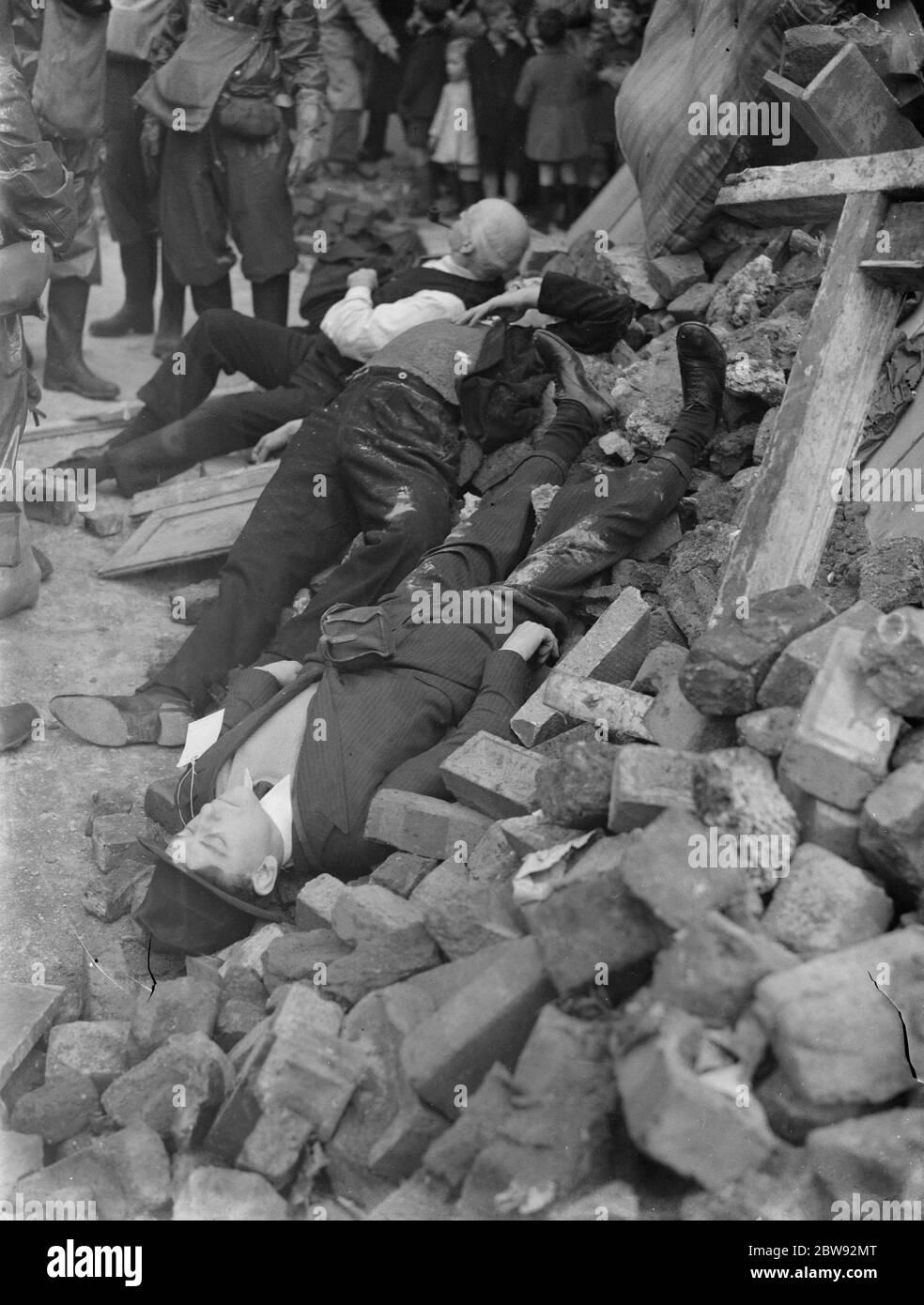 Air Raid Precaution exercise on Old Kent Road in London . Spectators gather round to see the ' casualties ' which are strewn across the rubble during the drill . 1939 . Stock Photo