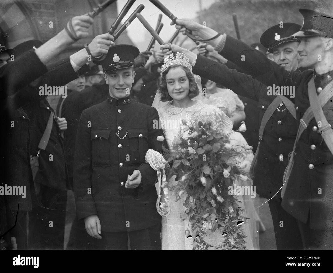 The wedding of special constable Mr R L King and Miss Winifred Latham in Plumstead , London . The bride and groom walk out through a guard of honour . 1939 Stock Photo