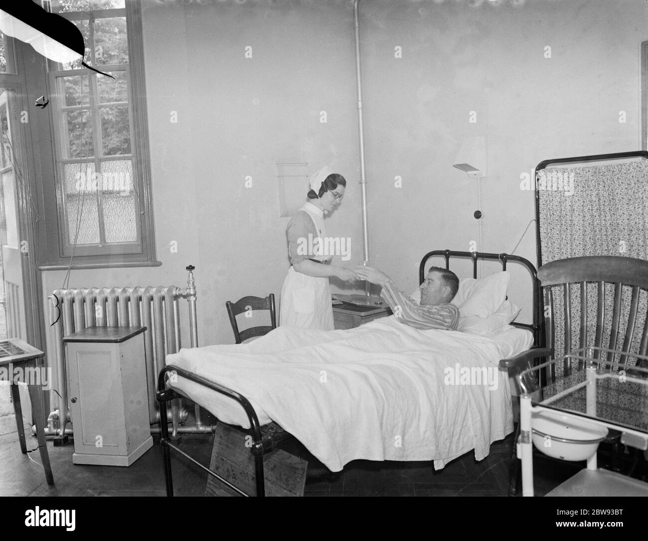 The Sidcup Cottage Hospital in Kent . A nurse tends to Mr Frank Ager , a patient in the men 's ward . 1939 Stock Photo