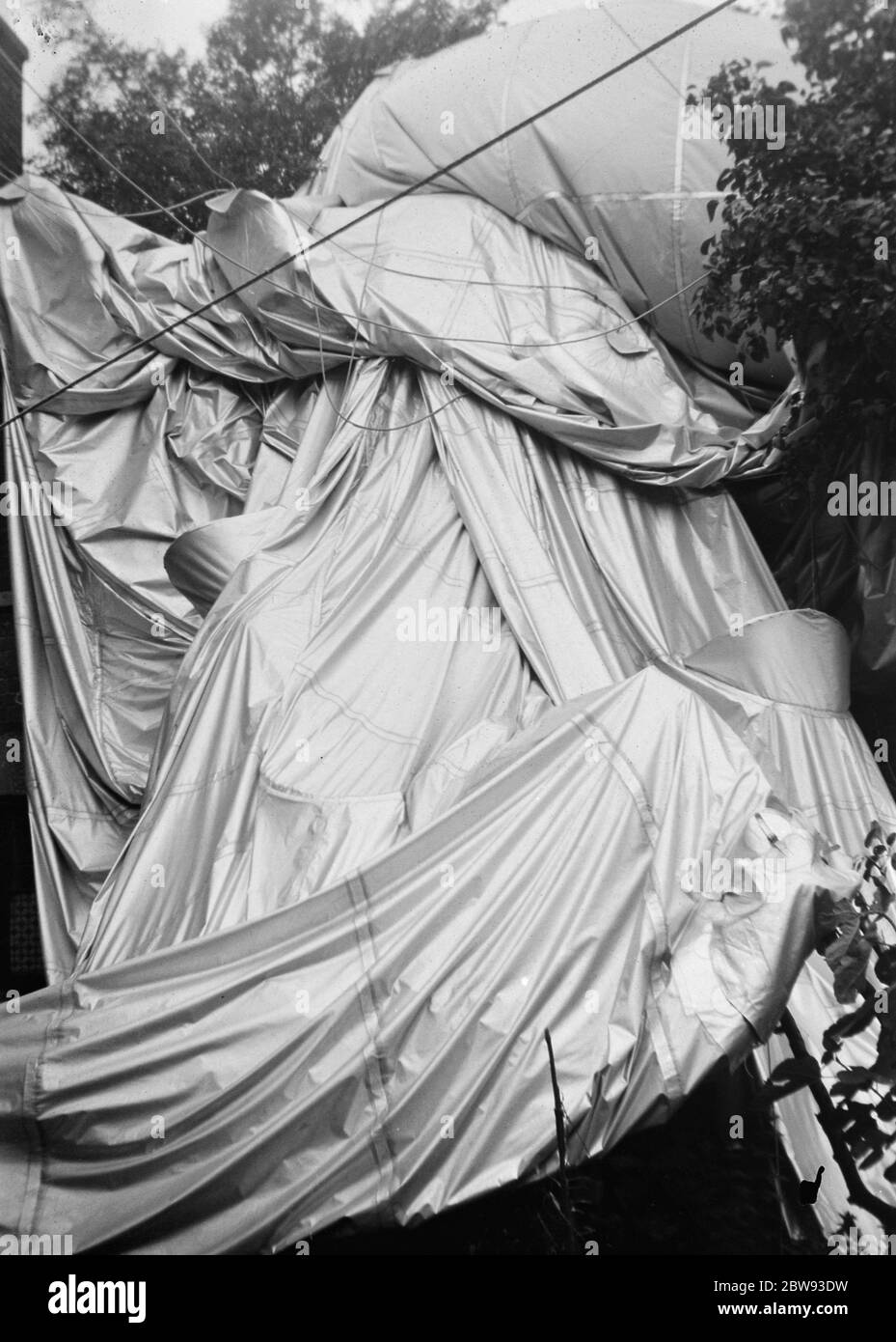 The aftermath following a barrage balloon explosion . The balloon lies in bushes after falling from the sky . 1939 Stock Photo