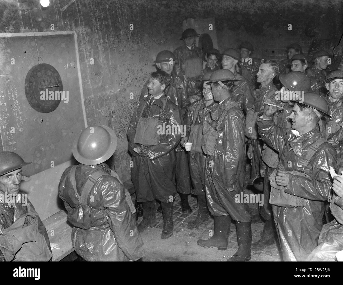 ARP ( Air Raid Precautions ) workers relax in their gas contamination suits playing a game of darts . 1939 Stock Photo